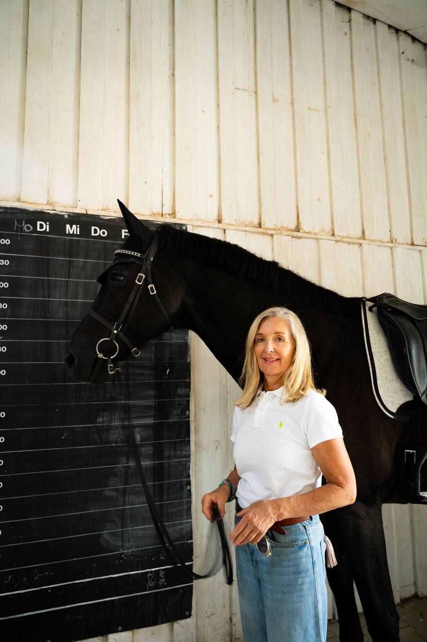 Jeanette Zehner mit einem Rappen an der Stallwand
